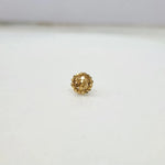 Front view of petite round floral 18K gold nose pin placed on a white surface emphasizing compact size and symmetry