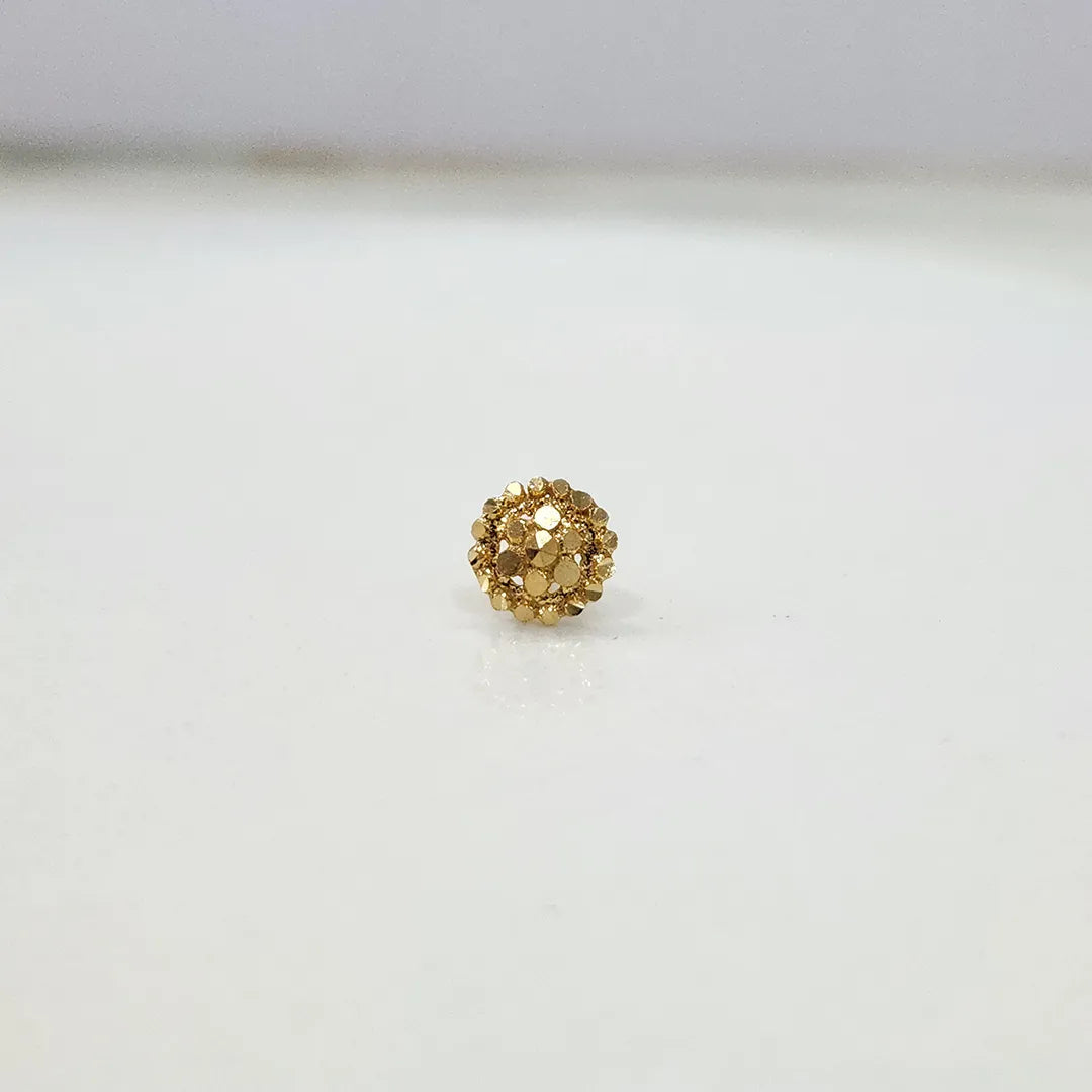 Front view of petite round floral 18K gold nose pin placed on a white surface emphasizing compact size and symmetry