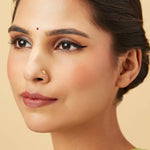 Woman with sleek hairstyle wearing a classic round floral 18K gold nose pin showcasing refined traditional styling