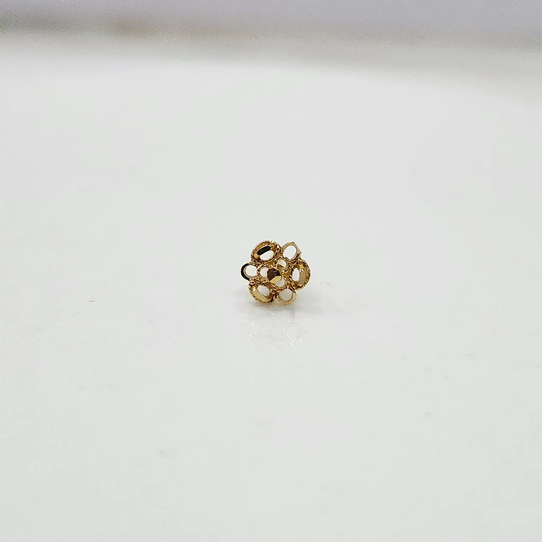 Side view of small 18K floral gold nose pin placed on a white surface showing its polished finish