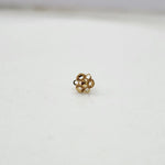 Side view of small 18K floral gold nose pin placed on a white surface showing its polished finish