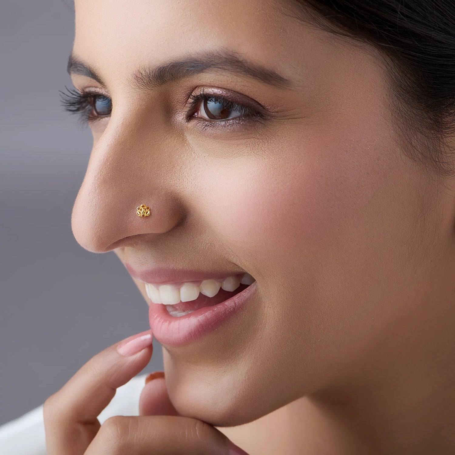 Woman smiling while wearing a delicate floral 18K gold nose pin showcasing an elegant everyday look