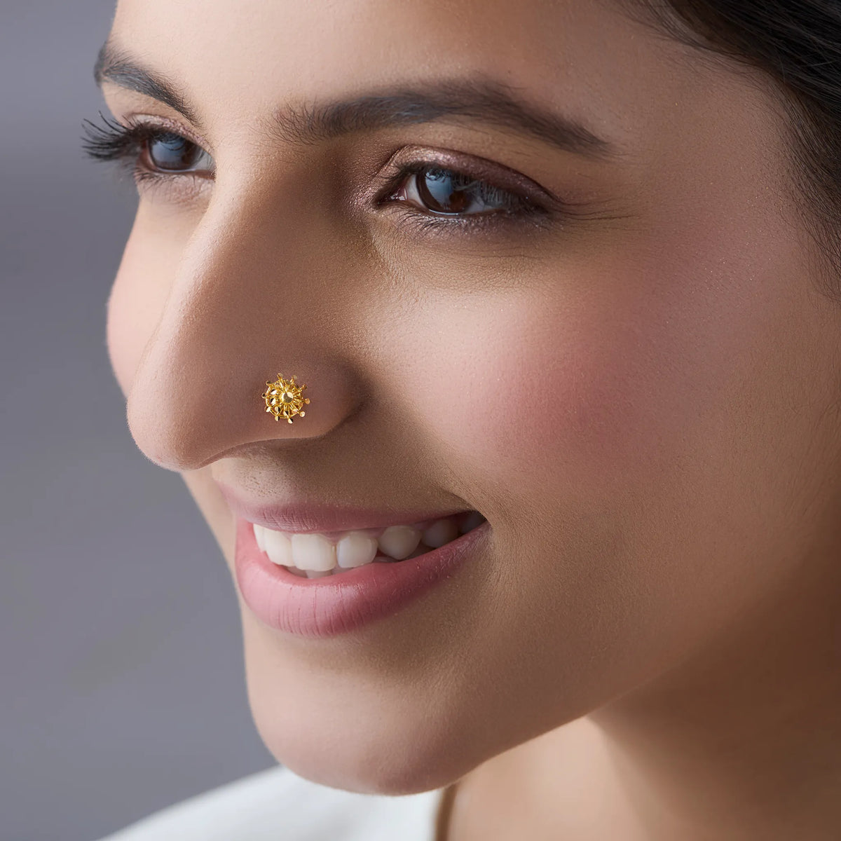 Woman wearing elegant gold nose pin design highlighting delicate floral motif for everyday elegance
