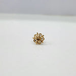 Side view of small floral 18K gold nose pin on a white surface showing its polished finish