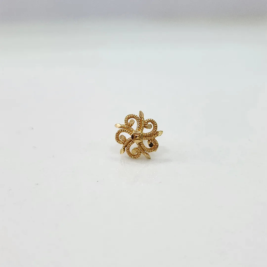 Front angle view of petite swirl 18K gold nose pin placed on a white surface emphasizing symmetry