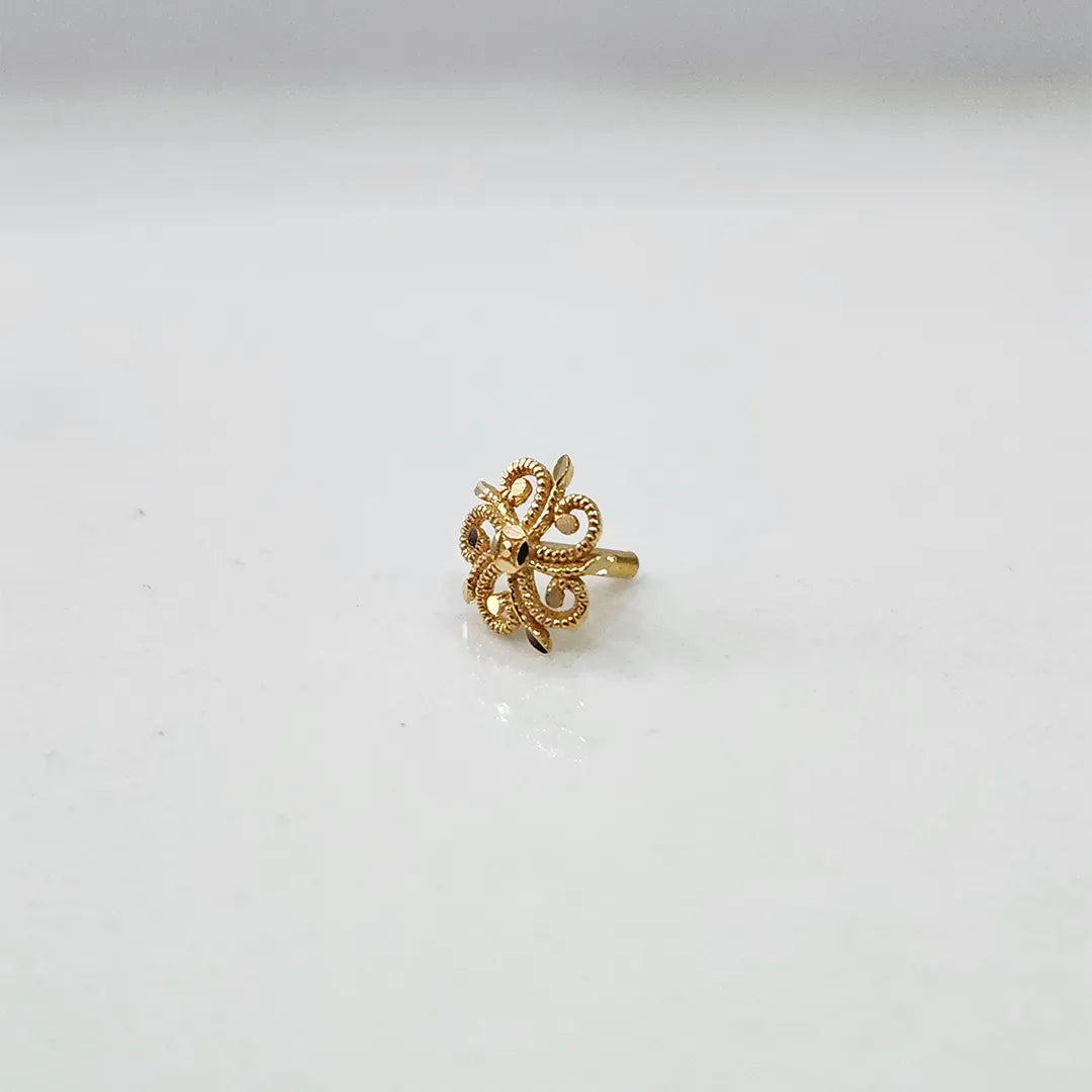 Side angle view of small swirl motif 18K gold nose pin on a white background highlighting its compact size