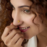 Woman wearing a small swirl design 18K gold nose pin smiling softly to highlight everyday elegance