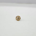 Close-up of tiny floral 18K nose pin gold on a clean white surface showcasing fine detailing
