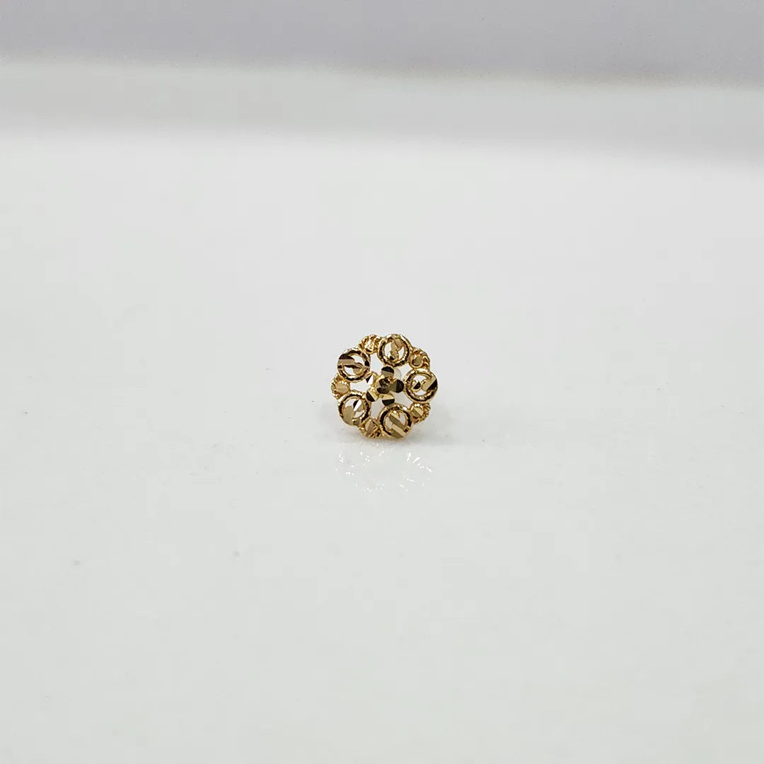 Close-up of tiny floral 18K nose pin gold on a clean white surface showcasing fine detailing