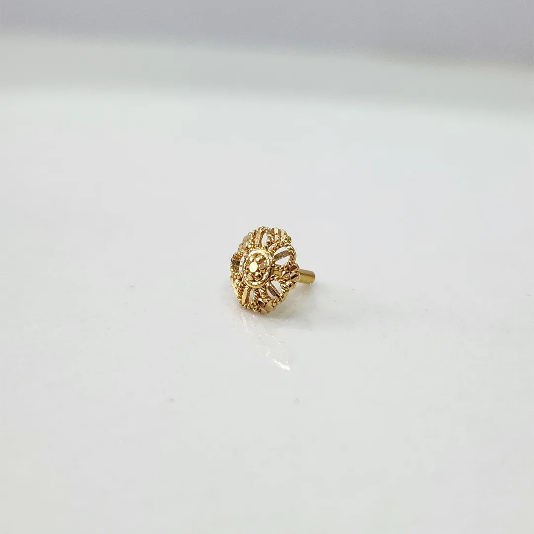 Side angle view of petite floral gold nose pin on a white surface emphasizing its lightweight and compact profile