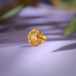 Close up of intricate floral inspired 18K gold nose pin placed on a soft lavender surface with leaf shadows highlighting fine detailing