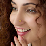 Woman with curly hair smiling while wearing a delicate floral 18K gold nose pin showing elegant everyday styling