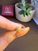 Hand holding a tiny floral 18K gold nose pin near a potted plant to showcase size and detailing