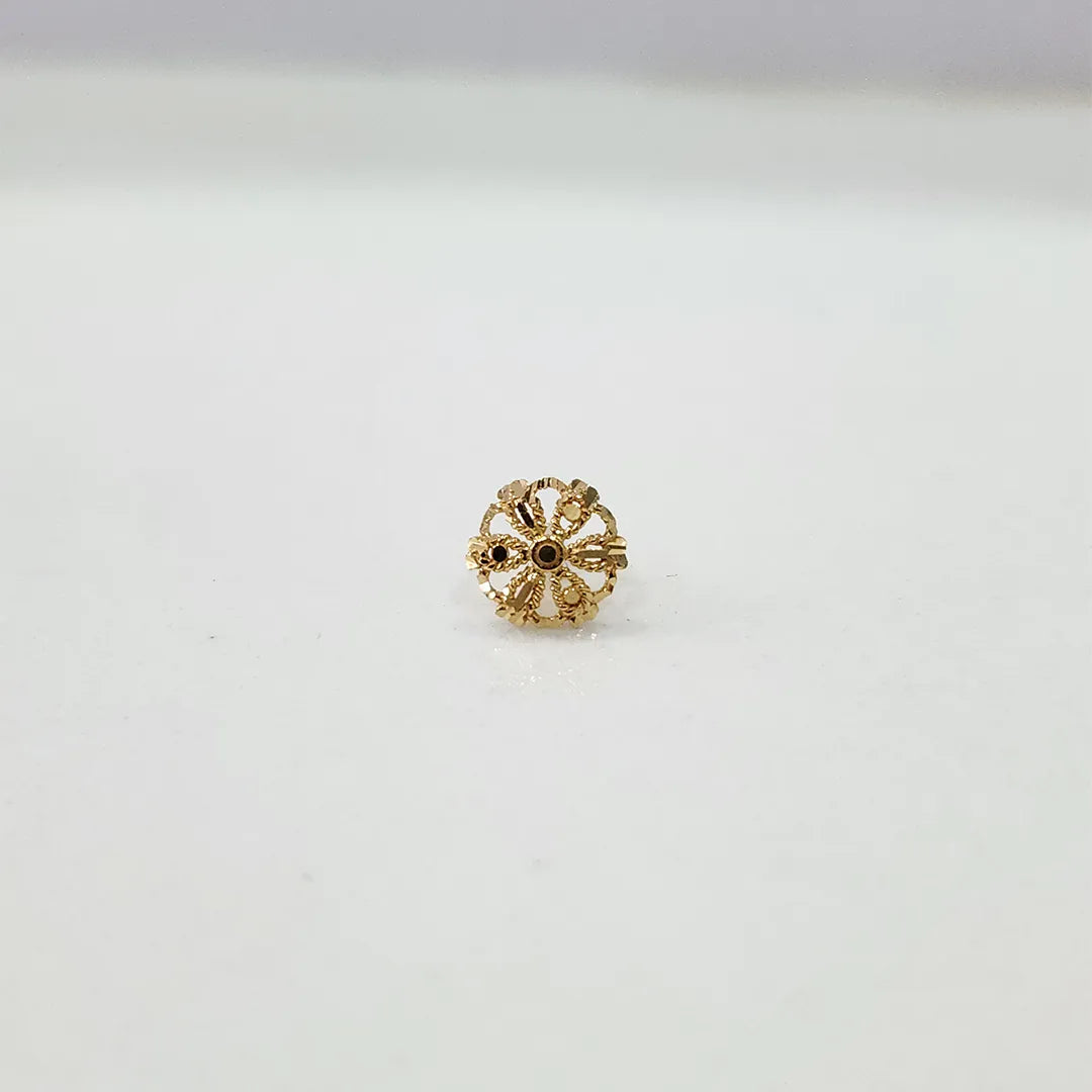 Side angle view of petite floral design gold nose pin on a white surface emphasizing its lightweight and minimal profile