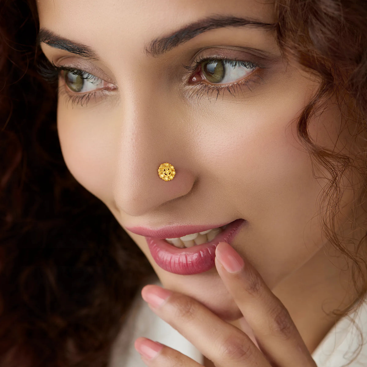 Woman wearing a floral gold nose pin showing elegant traditional inspired styling on the face