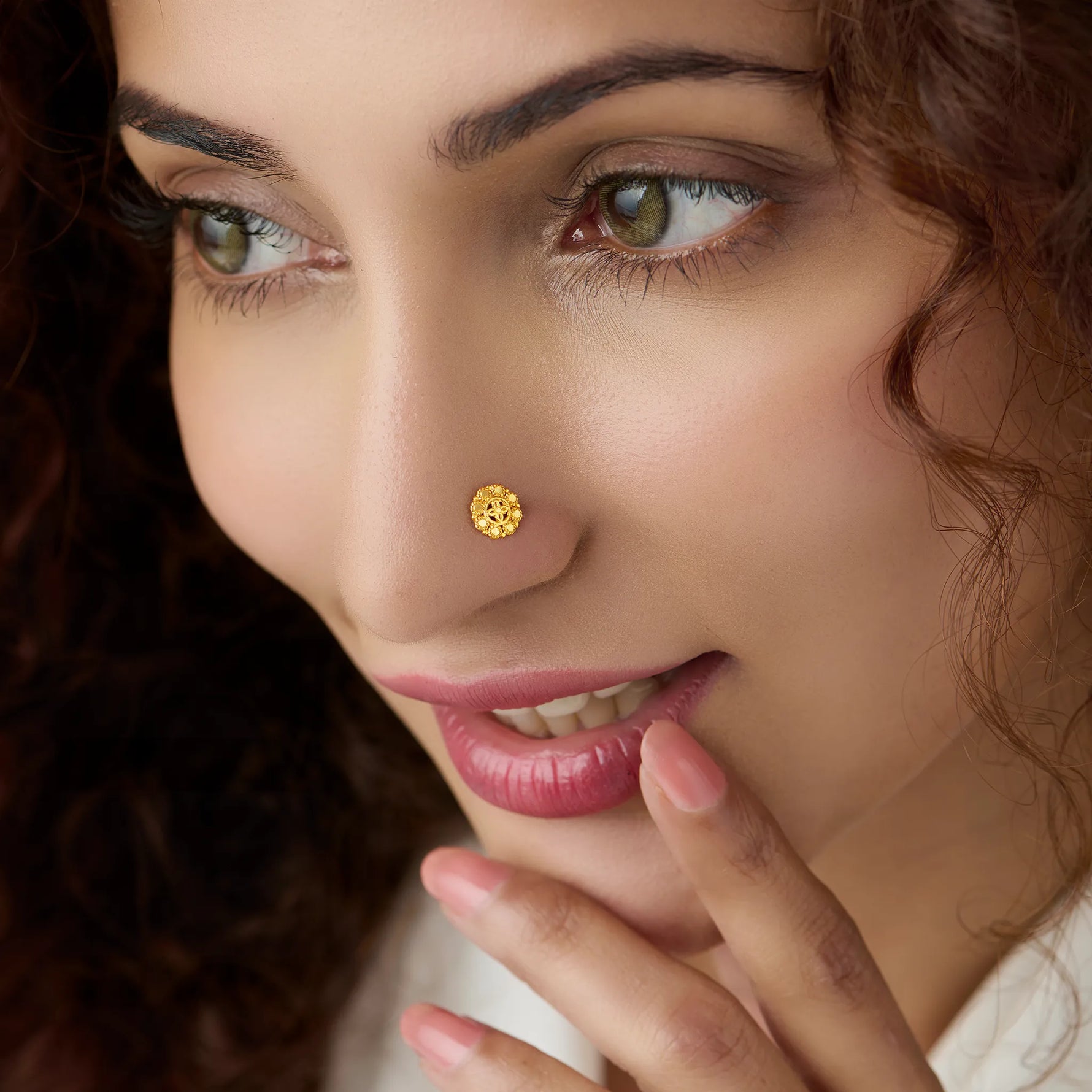Woman wearing a floral gold nose pin showing elegant traditional inspired styling on the face
