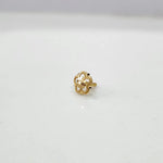Side view of the floral gold nose pin on a white surface highlighting its compact size and neat finish