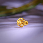 Close up of an intricate floral gold nose pin placed on a soft lavender surface highlighting detailed craftsmanship