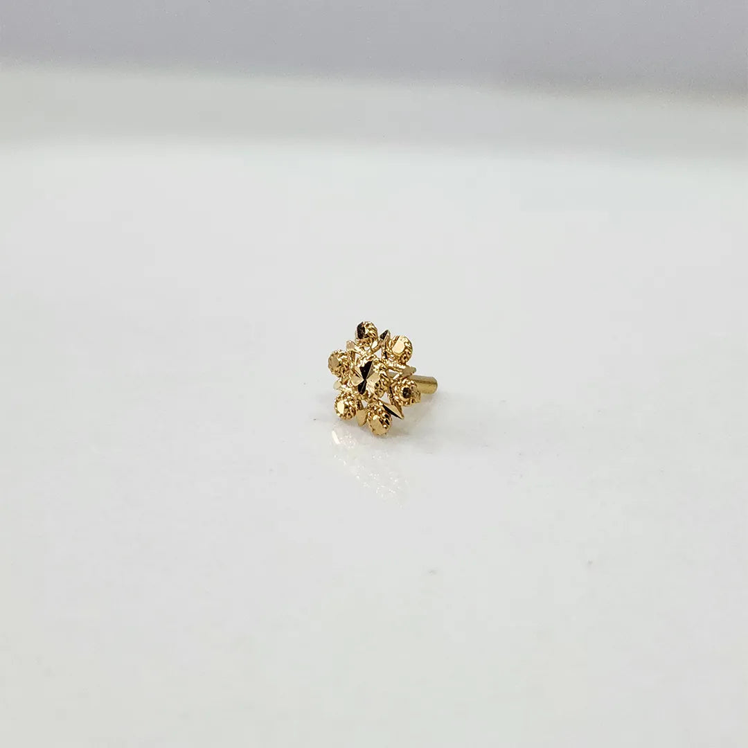 Close-up of tiny floral 18K nose pin gold on a clean white background displaying intricate design