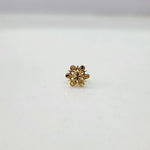 Small floral 18K nose pin gold on a white surface showing its fine handcrafted detailing