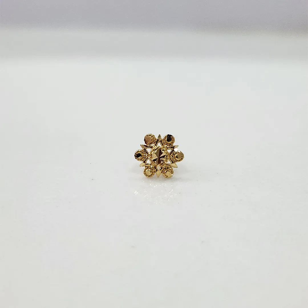 Small floral 18K nose pin gold on a white surface showing its fine handcrafted detailing