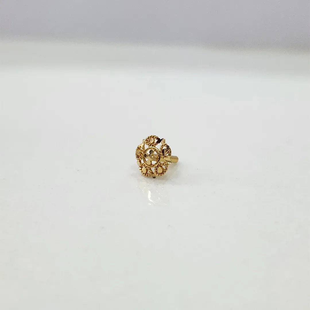 Side view of the floral gold nose pin on a white surface highlighting its depth and polished finish