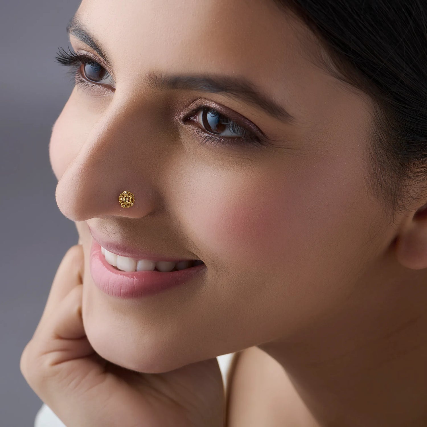 Woman wearing a delicate gold nose pin smiling gently showcasing an elegant everyday look