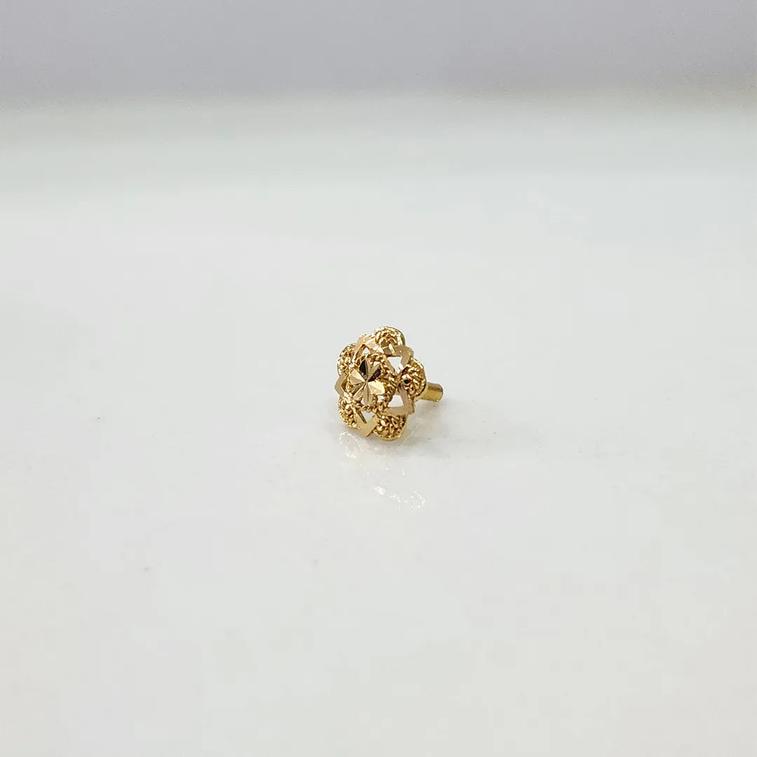 Front view of a floral 18K gold nose pin placed on a white surface highlighting its compact design