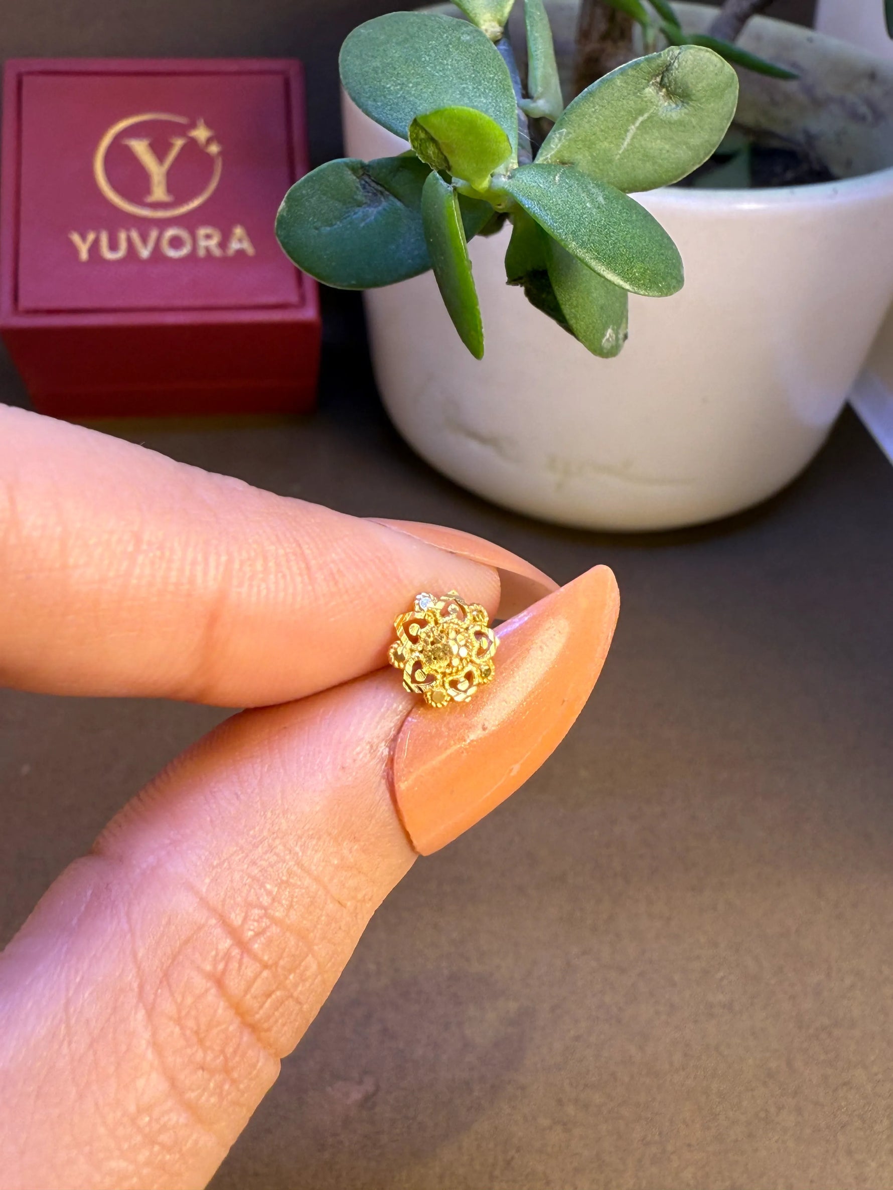 Hand holding tiny 18K nose pin gold to show its small size and delicate craftsmanship