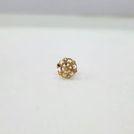 Side view of floral gold nose pin on a white surface showing compact size and detailing