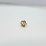 Side angle view of the floral gold nose pin on a white surface highlighting depth and fine craftsmanship