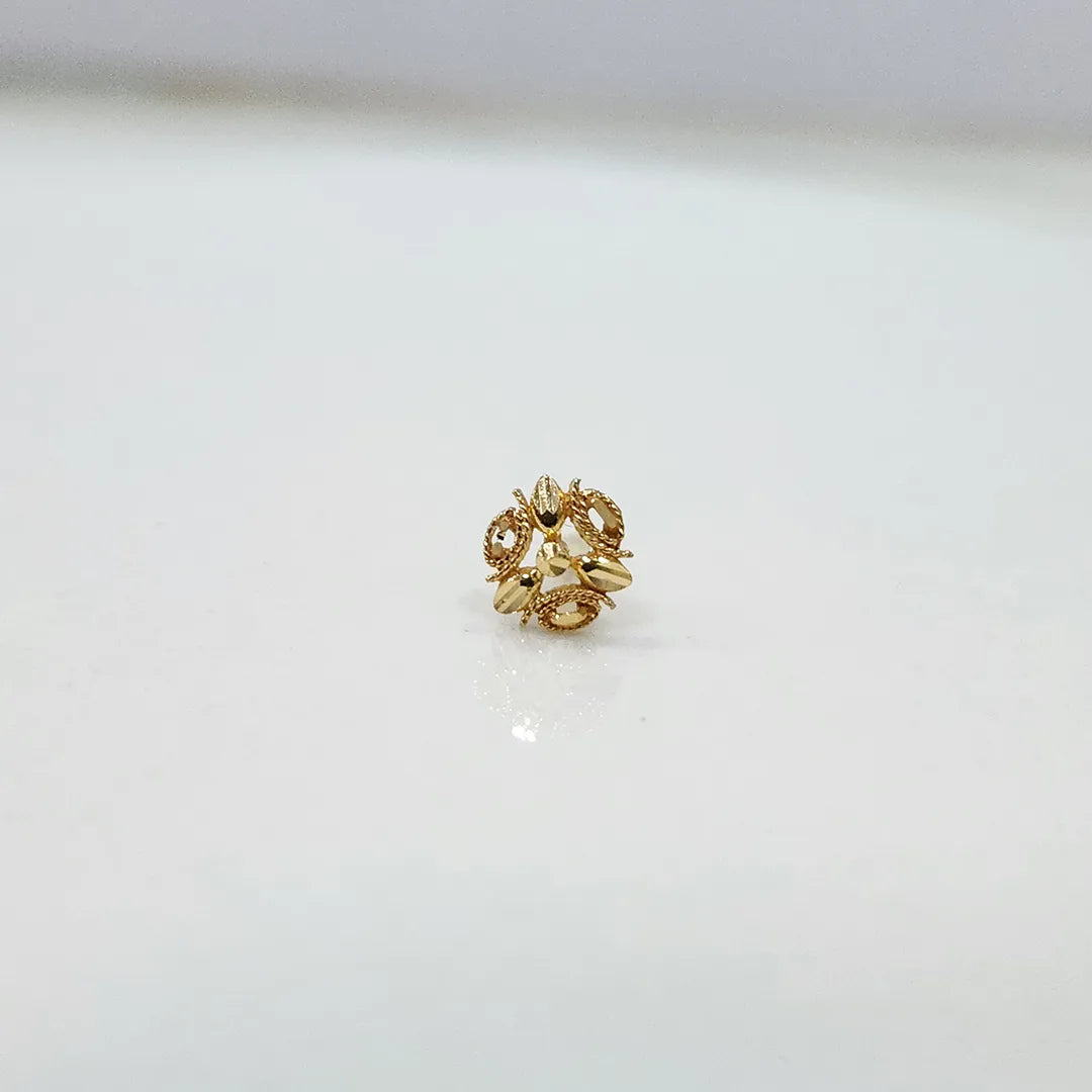 Side angle view of the floral gold nose pin on a white surface highlighting depth and fine craftsmanship