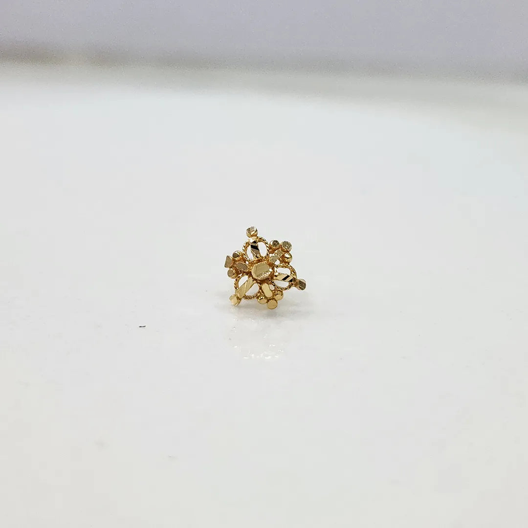 Side view of small 18K gold cluster nose pin placed on a white surface showing its polished finish
