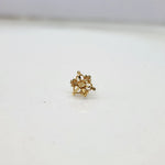 Side view of small 18K gold cluster nose pin placed on a white surface showing its polished finish