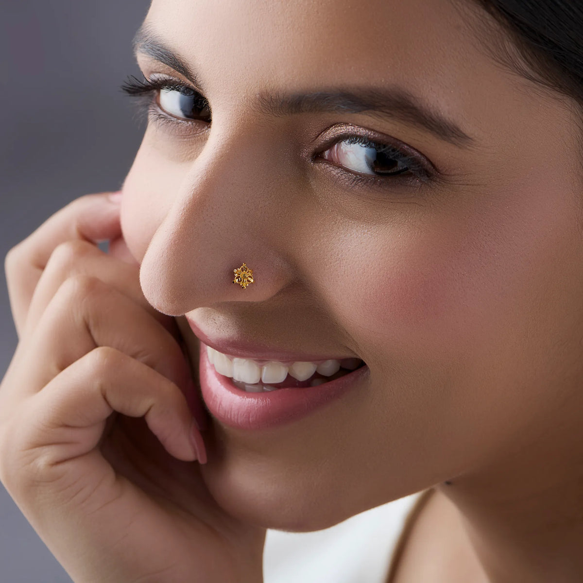 Woman wearing a delicate 18K gold cluster nose pin highlighting its elegant everyday appeal