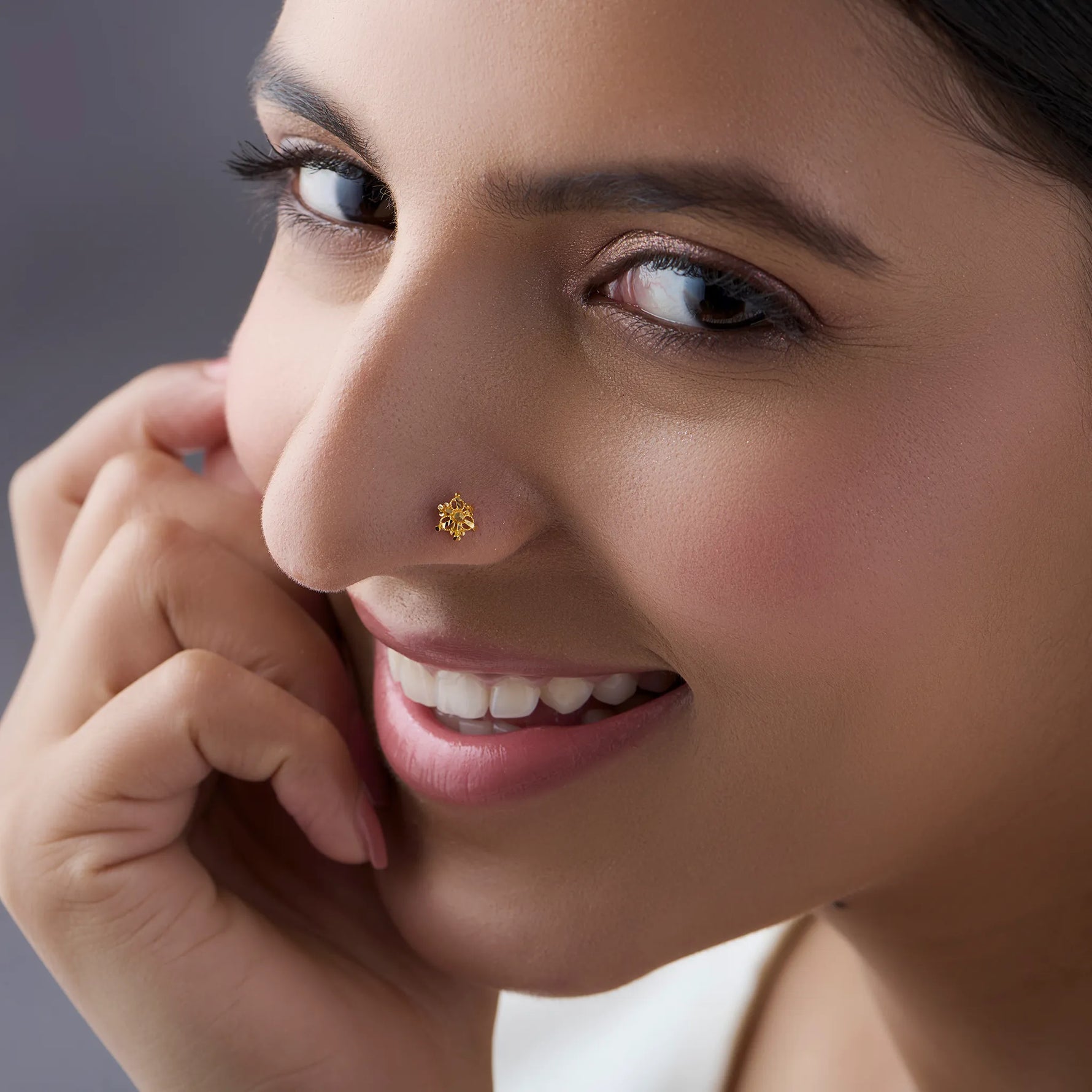 Woman wearing a delicate 18K gold cluster nose pin highlighting its elegant everyday appeal