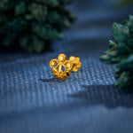 Close-up of floral 18K nose pin gold placed on a textured blue surface highlighting its intricate detailing