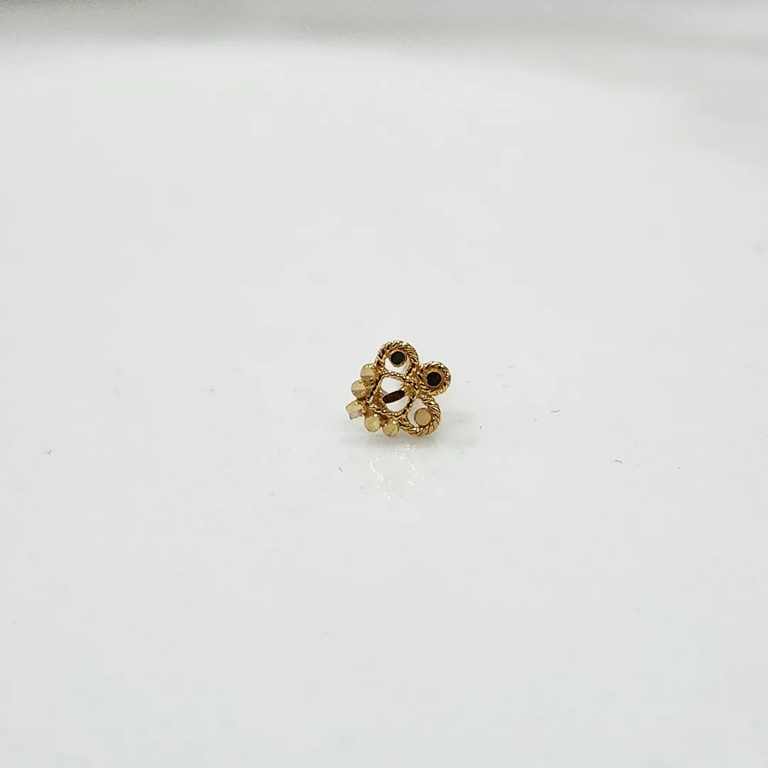 Close-up of floral 18K nose pin gold on a clean white surface highlighting its polished finish