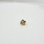 Close-up of floral 18K nose pin gold on a clean white surface highlighting its polished finish