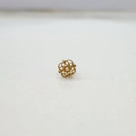 Side angle view of floral 18K gold nose pin on a white surface highlighting depth and polished finish