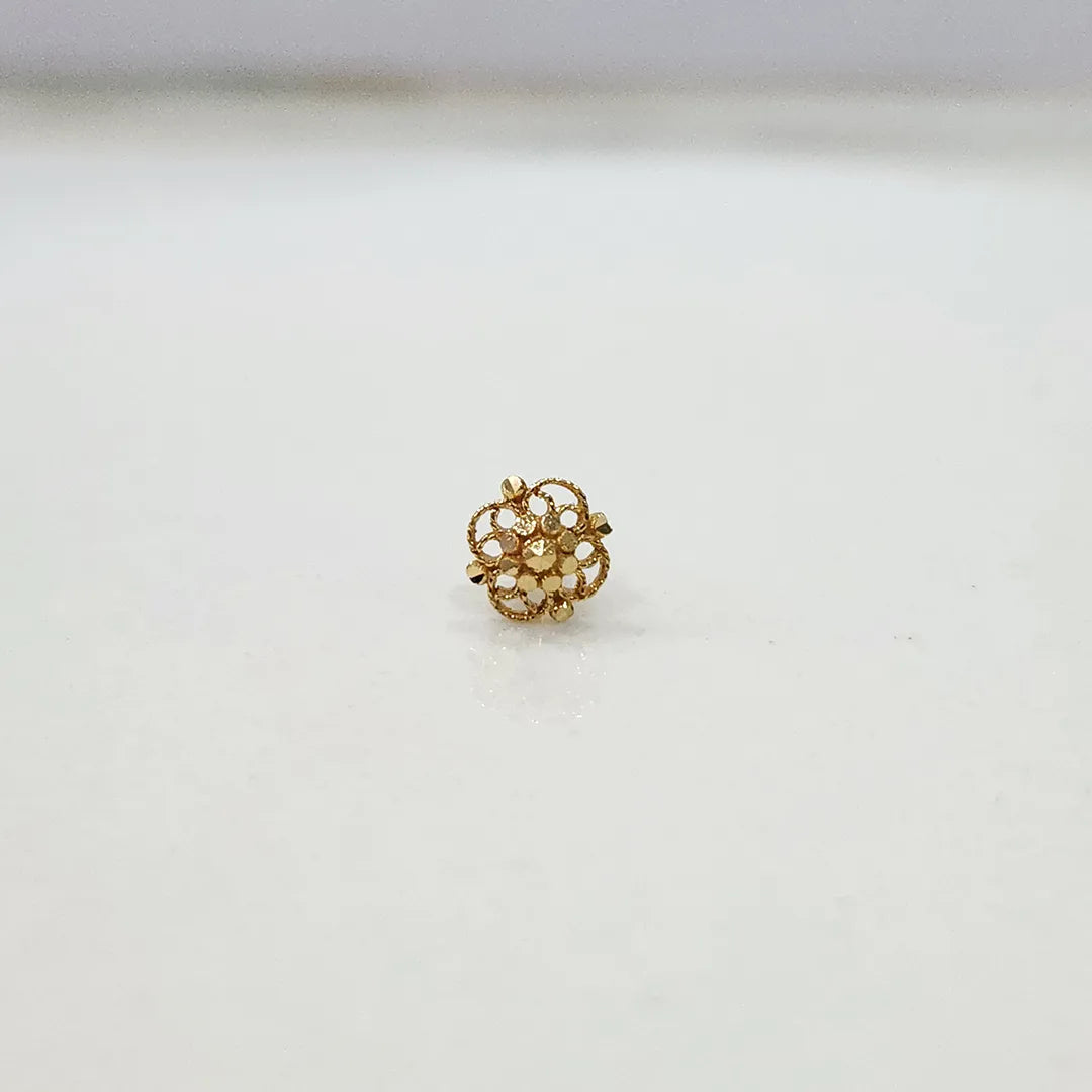 Side angle view of floral 18K gold nose pin on a white surface highlighting depth and polished finish