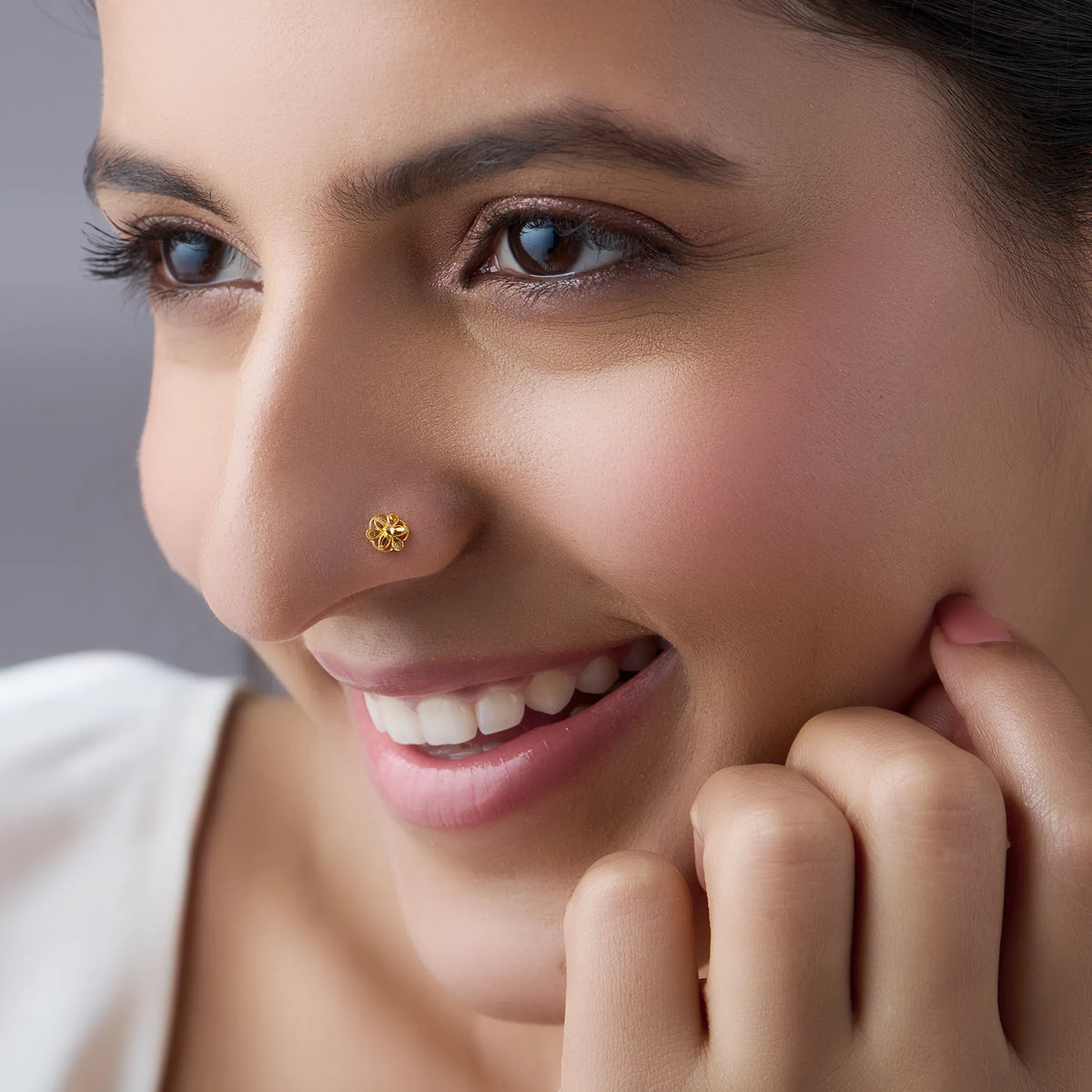 Smiling woman wearing a minimal 18K gold nose pin highlighting everyday wear style