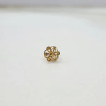 Side angle view of floral 18K gold nose pin on a white surface highlighting its compact and lightweight design