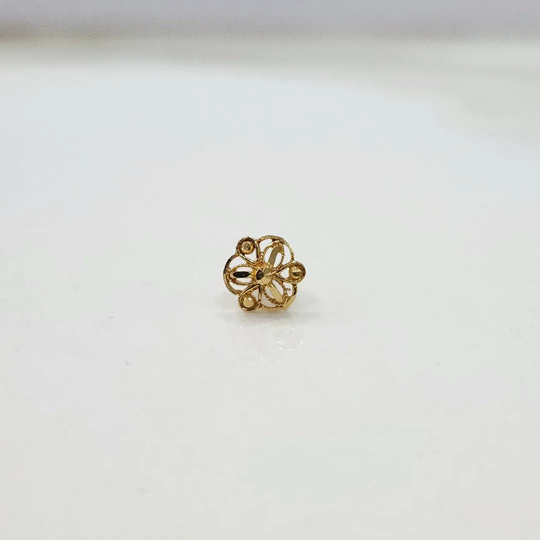 Side angle view of floral 18K gold nose pin on a white surface highlighting its compact and lightweight design