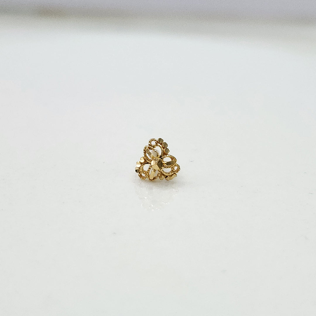 Front view of a tiny floral gold nose pin placed on a white background showing precise detailing and compact size