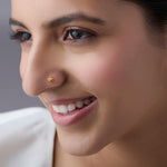 Woman wearing a small floral gold nose pin smiling softly showcasing a refined everyday jewellery look