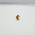 Front view of a tiny gold nose pin placed on a white surface highlighting its compact floral design
