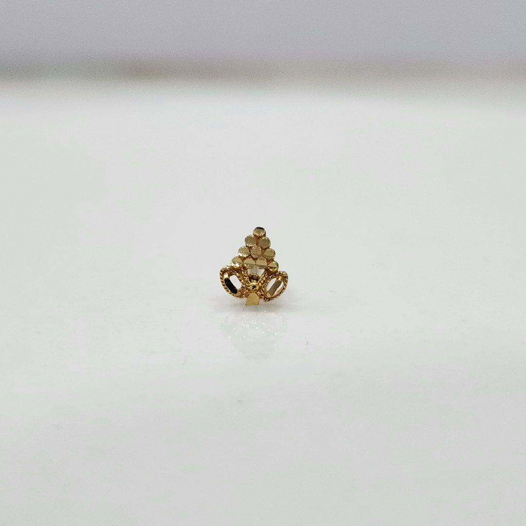 Side view of small 18K gold nose pin placed on a white surface showing its polished finish