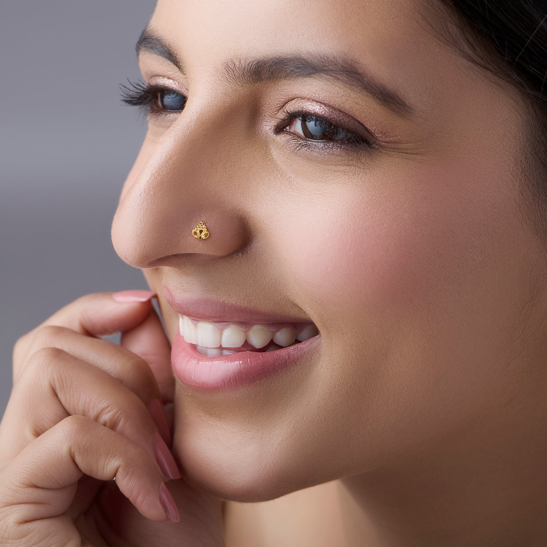 Woman smiling while wearing a delicate 18K gold nose pin showcasing its elegant everyday look