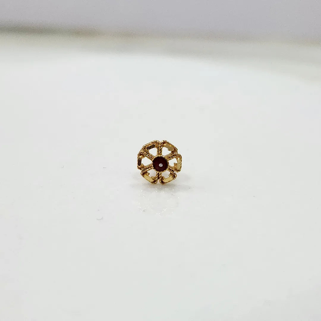 Side view of small floral 18K nose pin gold with red stone captured on a white background highlighting its polished finish